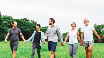 Group of diverse adults walking hand in hand in a park. Smiling, enjoying nature, and bonding....