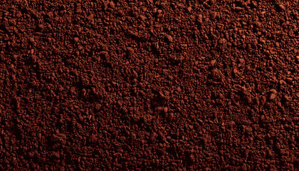 A close-up macro shot of freshly ground coffee, capturing the rich, dark brown particles with fine details. The texture of the coffee grounds reveals their coarse consistency and vibrant color, creati