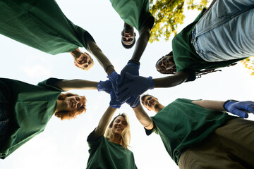 Group of volunteers putting hands together wearing green shirts