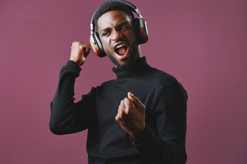 Young African American man enjoying music in stylish headphones, expressing joy and excitement...