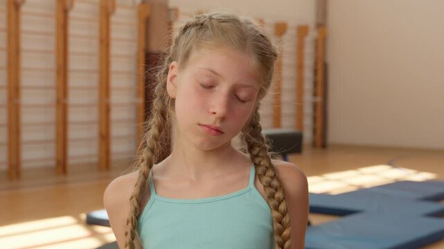 Sad girl Caucasian child kid portrait upset frustrated schoolgirl pupil student young sportswoman gymnast looking at camera shrug shoulders in gym sport training workout school education teen fitness
