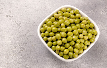 Canned green peas in a plate on a gray background