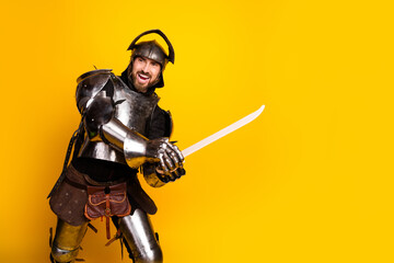 Man Dressed as a Knight Posing With a Sword on a Bright Yellow Background