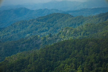Obraz premium The stunning view of the sun set from a tourist's standpoint with a foggy hill and a background of a golden sky in National Park, Thailand. Rainforest. Bird's eye view. Aerial view.