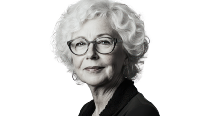 A thoughtful senior woman with curly white hair and glasses, smiling gently, against a plain background.