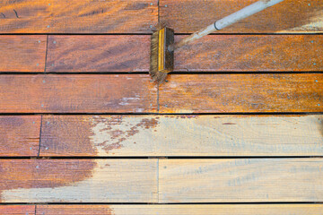 Close-up of a wooden deck being stained with a brush for protection and maintenance during a home...