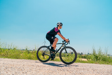 Obraz premium Cyclist riding along a rural path in bright sunlight with wind turbines in the background