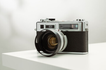 A vintage film camera sits elegantly on a white surface, showcasing its timeless design.