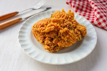 Fried chicken with knife and fork in a white plate on white background, 