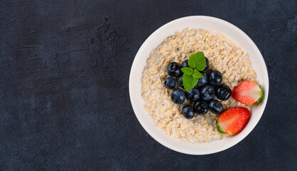 Milk porridge prepared for breakfast with blueberries, strawberries and bananas