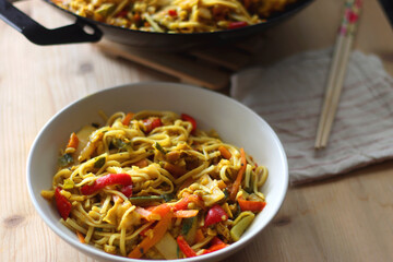 Bowl of stir fry vegetables and noodles, served on the table. Selective focus.
