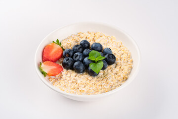 Milk porridge prepared for breakfast with blueberries, strawberries and bananas