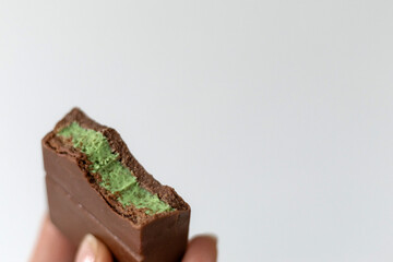 Bitten chocolate bar of trend dessert Dubai chocolate with green kataifi and pistachio paste, cream isolated on white background