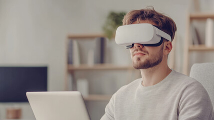Young man using virtual reality headset while sitting at a desk with laptop in modern home office setting