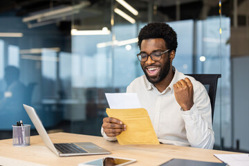 Successful businessman holding postal envelope, man received notification letter with successful achievement results. Man holding hand up, celebrating triumph and victory.