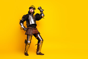 Portrait of a knight in vintage armor posing on a bright yellow background with a playful and dramatic demeanor