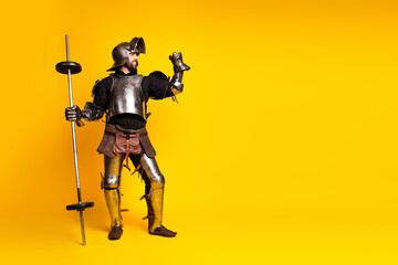 Medieval knight in full armor with a weightlifting barbell over a vibrant yellow background