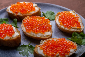 Canapes with red caviar on a plate decorated with cilantro