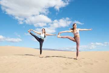 Obraz premium women doing yoga and stretching exercises on the beach 