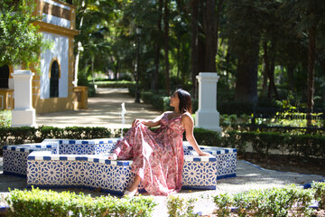 beautiful young brunette woman in a long floral patterned dress is sitting in a star-shaped...