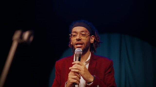 Showman performing on stage, portrait of african american male host with mic. Attractive black male person performing comical monologues, stand-up comedy performance, charismatic arab guy talking