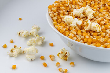 Corn for popcorn. Plate with corn kernels on white background.