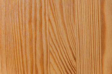 A close-up of a wooden surface with a natural grain pattern, showing warm tones and textured lines.