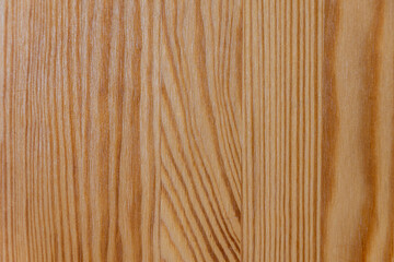 A close-up of a wooden surface with a natural grain pattern, showing warm tones and textured lines.