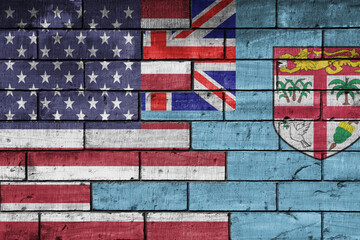 colourful painted big flag of united states of america and flag of Fiji on a massive old brick wall background. concept