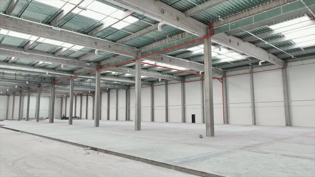 Footage of bright modern logistics warehouse inside. Drone view of interior of empty huge industrial area. Storage of good. Indoors. Business. Transportation concept. Packaging. Concrete floor