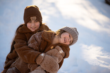 Two girls are happily sledding, hugging each other, down a snowy hill.