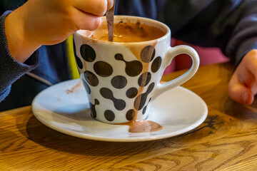 child drinking hot chocolate in a mug in a cafe. a cup with a dirty drink, spilling chocolate