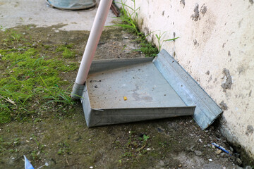 A dustpan made of zinc or light steel sheet, is outside the house.