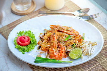 Pad Thai is a popular Thai street food dish. It consists of stir-fried rice noodles, vegetables, and meat or seafood. This dish is served with a lime wedge and is garnished with fresh herbs.