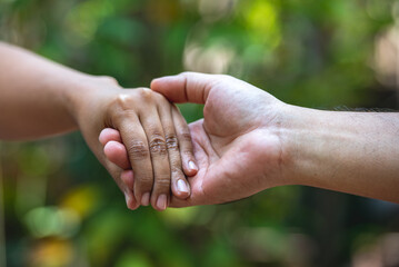 A close up of two people holding hands with a blurred background