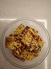 Delicious homemade dessert squares topped with a crunchy layer, beautifully arranged in a clear glass bowl on a light countertop