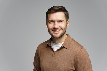 Smiling man with brown shirt and light background posing for a friendly portrait