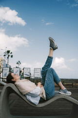 A woman lies on a concrete bench and looks at the sky
