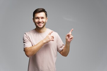 Smiling man in neutral shirt gestures enthusiastically with both hands against a soft gray backdrop