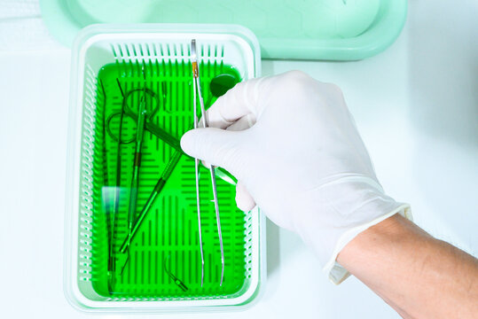 Dentist man putting items in sterilization tray for dental office items. Dental office, asepsis. Closed angle, close-up.