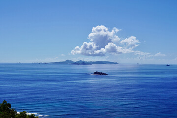 The unusually calm water of the Atlantic is a stunning blue in this photo featuring St. Barths on the horizon with a fluffy cumulus cloud over it and Pelican Key in the center. © Margaret LN Brooks