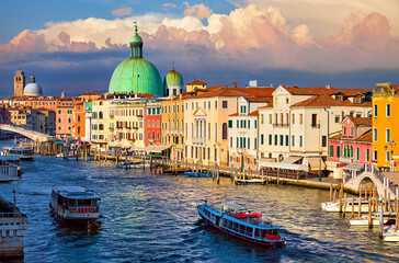 Grand Canal in Venice Italy. Panoramic view at the csenic cityscape of Venezia and cathedral Dome. Motorboats on water. Sunny summer evening with dramatic sky sunset. Popular travel destination