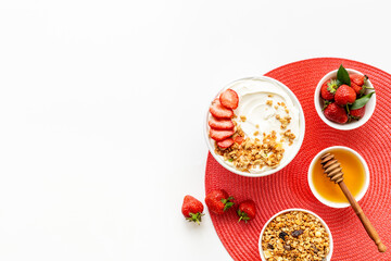 Bowl with yogurt and oatmeal served with honey and strawberry, top view