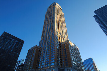Fototapeta premium Tall building with numerous windows, reflecting the setting sun's warm golden light.
