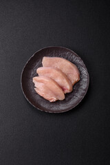 Obraz premium Fresh chicken fillet on a dark concrete table with spices and herbs