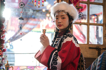 Young pretty Mongolian girl in traditional costume posting in Tibetan style room