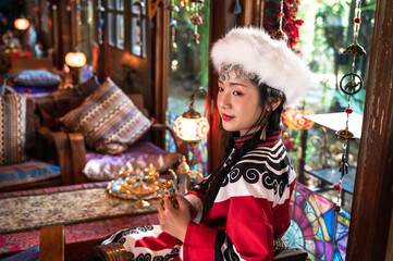 Young pretty Mongolian girl in traditional costume sitting in Tibetan style room