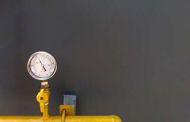 Water, oil or gas pressure gauge with yellow pipe installed on gray wall with copy space. Value...
