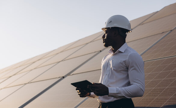 African American Engineer Inspecting Solar Panels With Digital Tablet