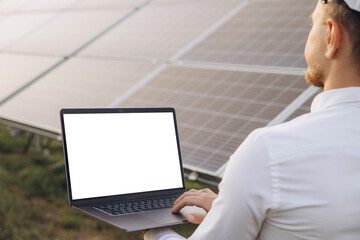 Man Using Laptop Near Solar Panels for Green Energy
